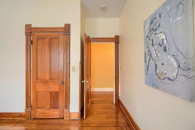 hall with baseboards and wood finished floors