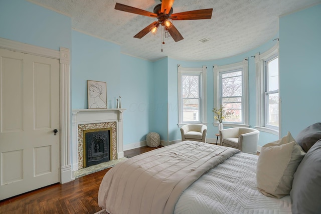 bedroom featuring baseboards, visible vents, dark wood finished floors, a fireplace with flush hearth, and a textured ceiling