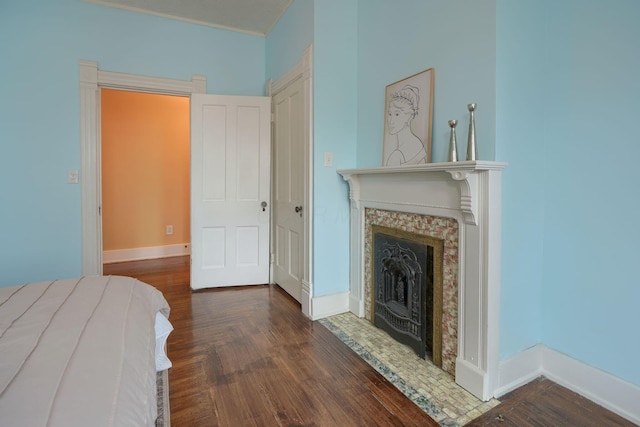 bedroom with a fireplace, baseboards, and wood finished floors