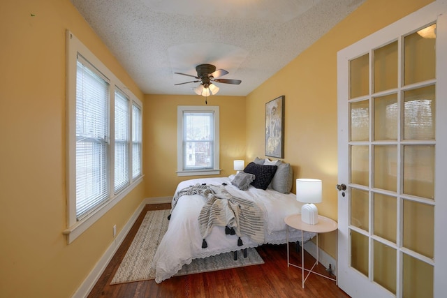 bedroom with a textured ceiling, ceiling fan, wood finished floors, and baseboards