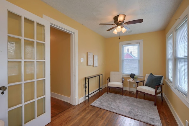 living area featuring a textured ceiling, wood finished floors, visible vents, and baseboards