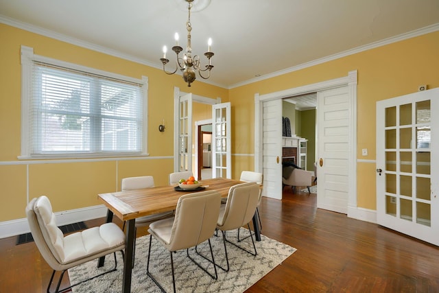 dining area with dark wood-style floors, ornamental molding, a brick fireplace, a chandelier, and baseboards