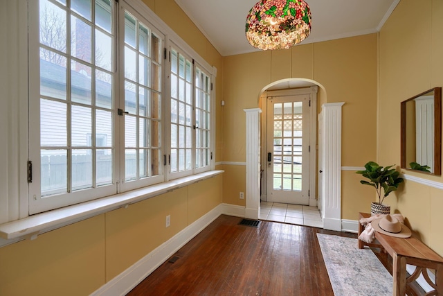 doorway to outside featuring baseboards, crown molding, visible vents, and hardwood / wood-style floors