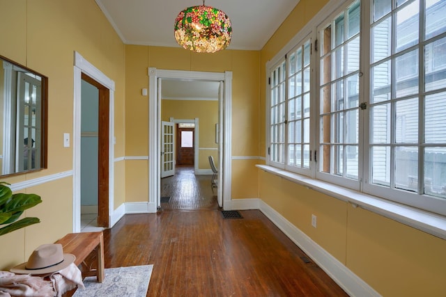 corridor featuring dark wood-style flooring, visible vents, crown molding, and a healthy amount of sunlight