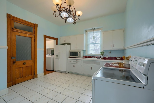 kitchen featuring washer / clothes dryer, an inviting chandelier, light tile patterned flooring, a sink, and white appliances