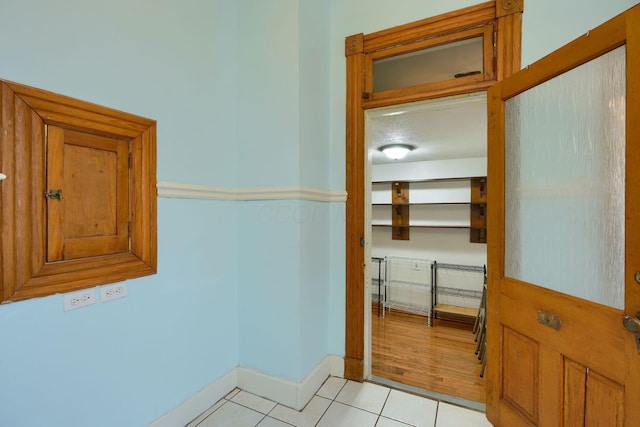 corridor featuring light tile patterned floors and baseboards