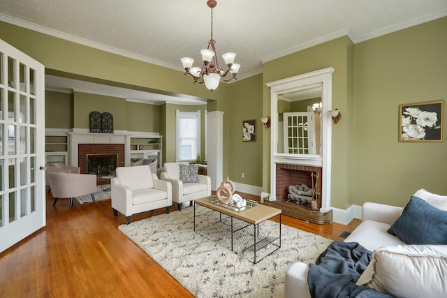 living area with ornamental molding, a fireplace, wood finished floors, and baseboards