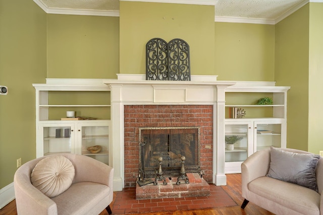 living area with a textured ceiling, a fireplace, ornamental molding, and wood finished floors