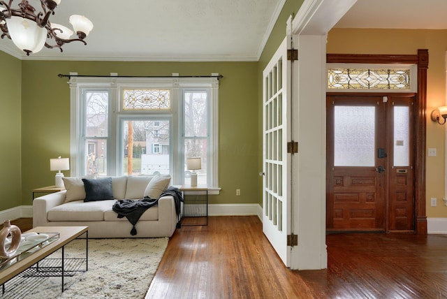 interior space with baseboards, hardwood / wood-style floors, ornamental molding, and a notable chandelier