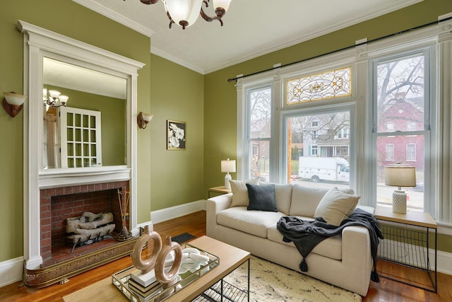 living area with crown molding, a fireplace, an inviting chandelier, wood finished floors, and baseboards