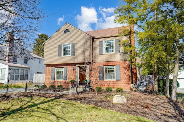 view of front facade featuring fence, a front lawn, and brick siding