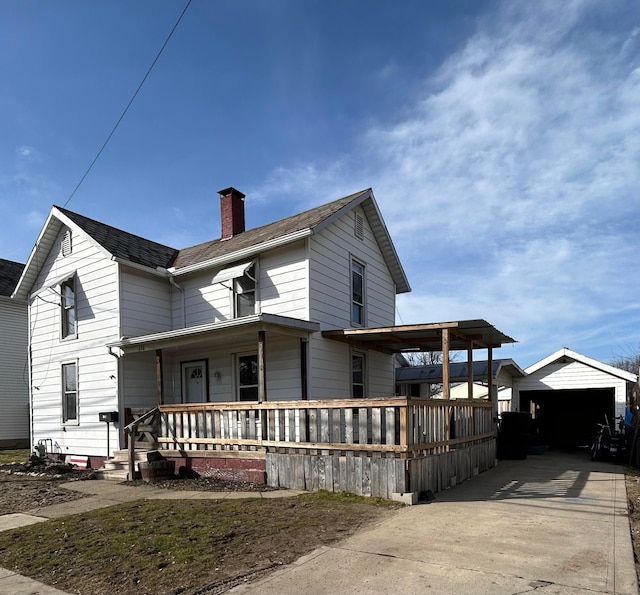 view of front of house featuring an outbuilding, covered porch, driveway, and a chimney