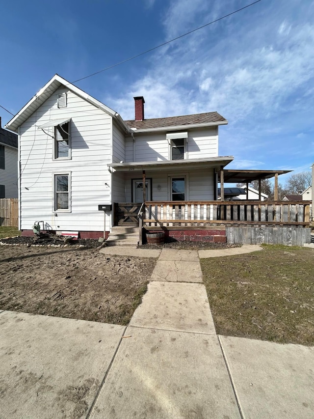 rear view of property featuring a porch and a chimney