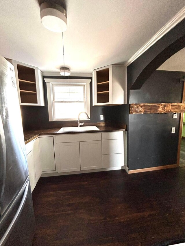 kitchen featuring open shelves, dark countertops, a sink, and freestanding refrigerator