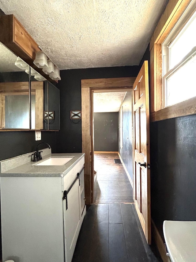 bathroom featuring baseboards, visible vents, wood-type flooring, a textured ceiling, and vanity