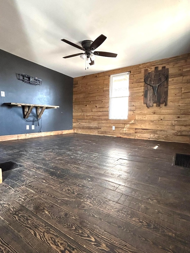 interior space with ceiling fan, wood walls, and wood-type flooring