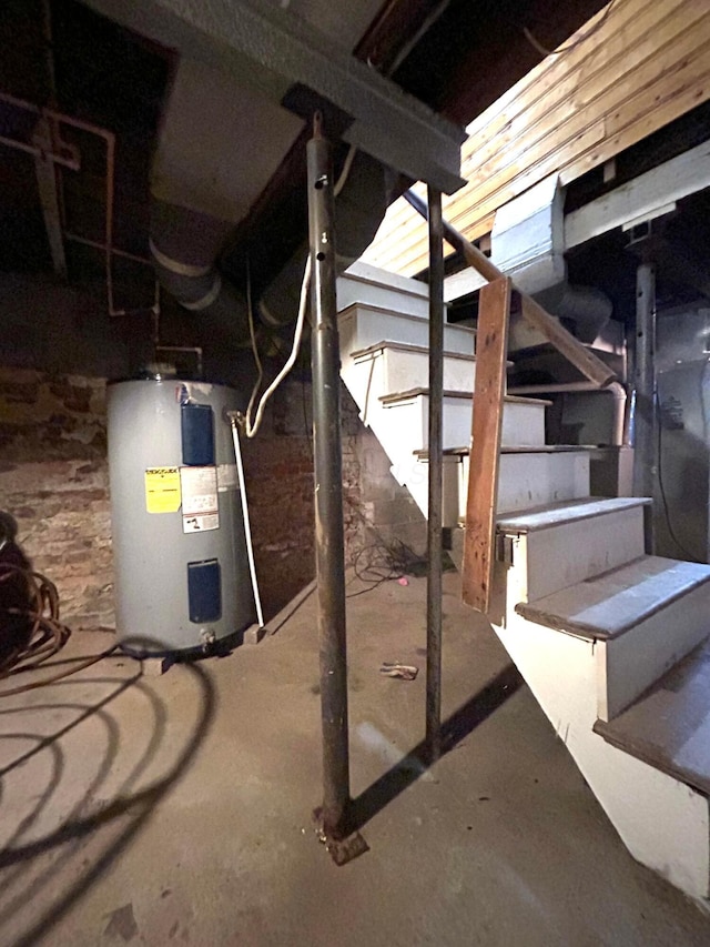 unfinished basement featuring electric water heater and stairs