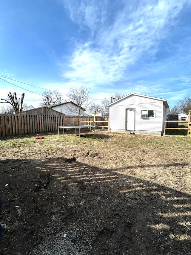 view of yard featuring a trampoline, fence, and an outbuilding