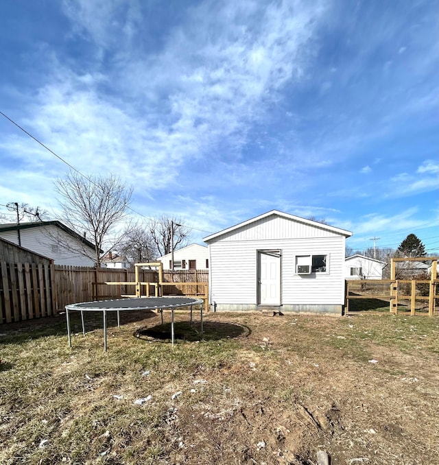 view of outdoor structure with a trampoline, an outbuilding, and a fenced backyard