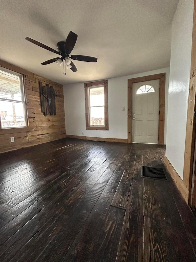 entryway with baseboards, wood walls, hardwood / wood-style flooring, and a ceiling fan