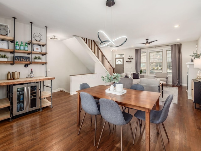 dining space featuring baseboards, dark wood-style floors, wine cooler, stairs, and a bar