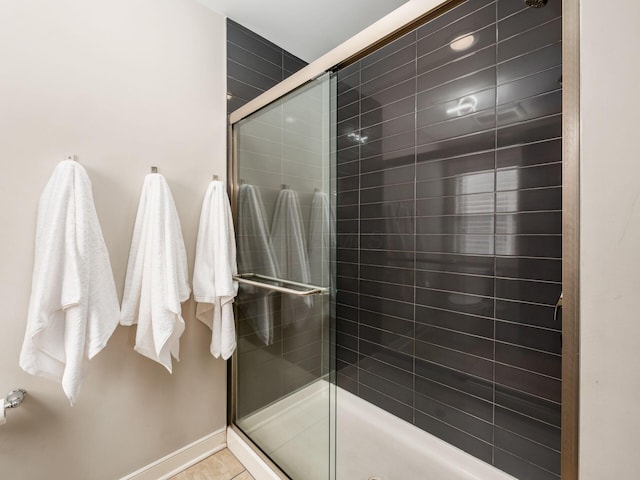 full bathroom with a shower stall and baseboards