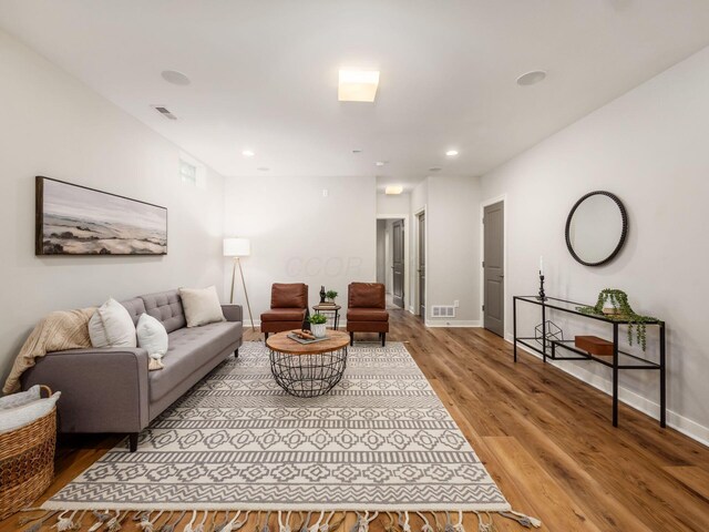 living area featuring recessed lighting, visible vents, baseboards, and wood finished floors