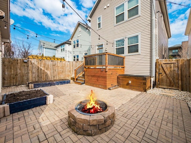 rear view of property featuring a fire pit, a patio area, a fenced backyard, and a wooden deck