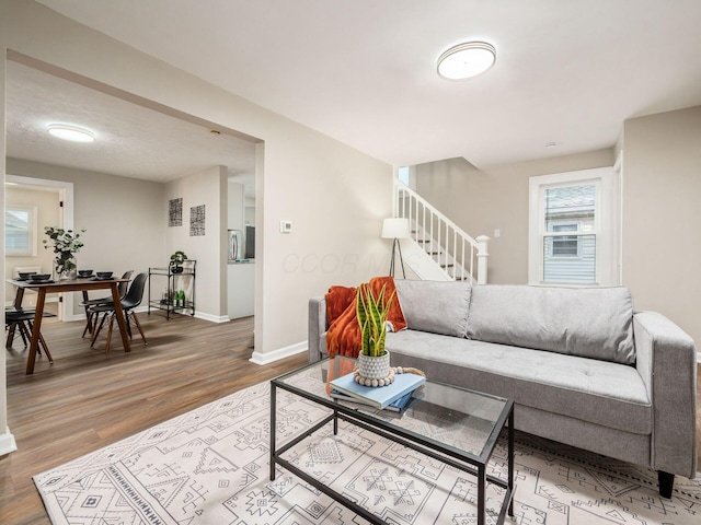 living area with stairway, wood finished floors, and baseboards