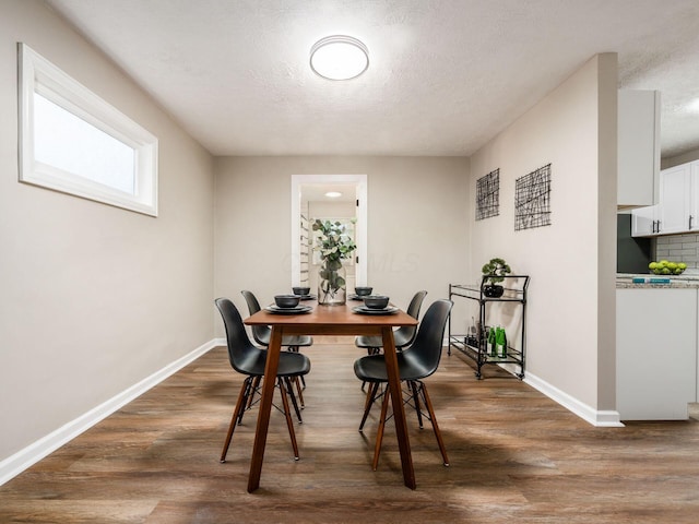 dining space featuring a textured ceiling, dark wood-style flooring, and baseboards