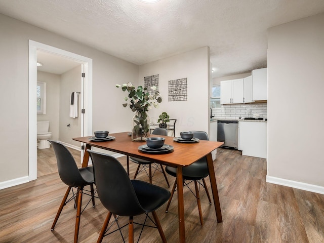 dining room with a textured ceiling, baseboards, and wood finished floors