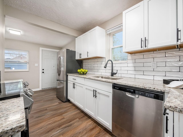 kitchen with white cabinets, dark wood finished floors, stainless steel appliances, and a sink