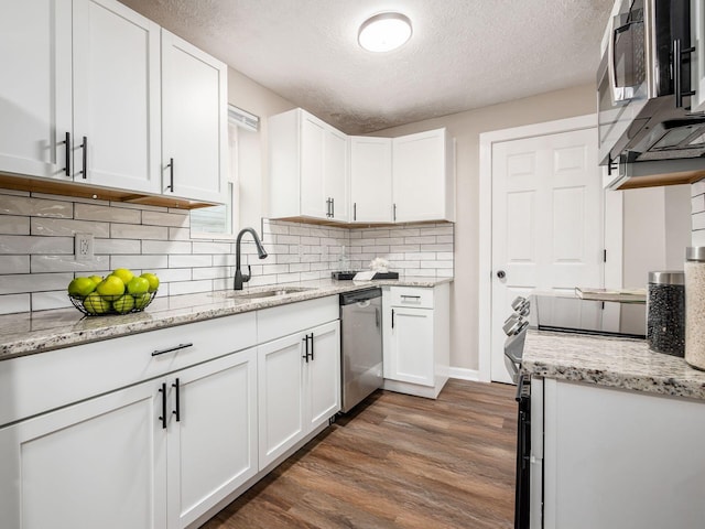 kitchen featuring tasteful backsplash, appliances with stainless steel finishes, dark wood-type flooring, white cabinets, and a sink