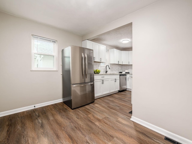 kitchen with tasteful backsplash, visible vents, white cabinets, stainless steel appliances, and a sink