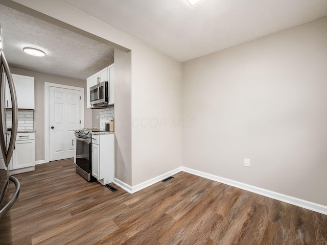 kitchen with stainless steel appliances, visible vents, baseboards, backsplash, and dark wood-style floors