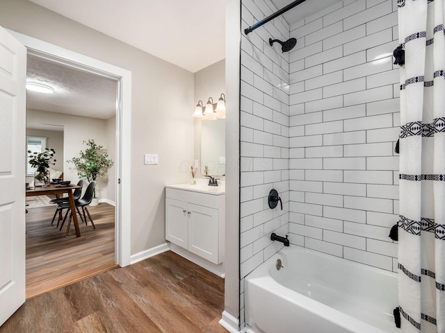 full bath with a textured ceiling, wood finished floors, vanity, baseboards, and shower / tub combo with curtain