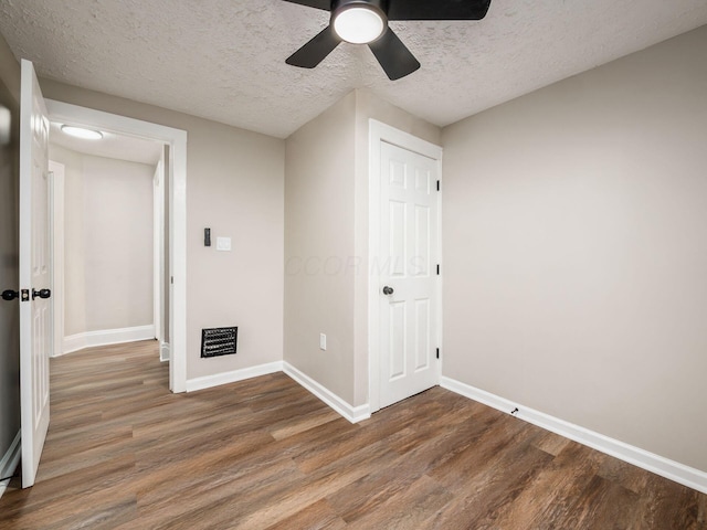 unfurnished bedroom with a textured ceiling, ceiling fan, wood finished floors, baseboards, and a closet