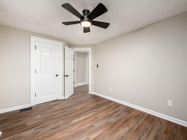 unfurnished bedroom with a textured ceiling, wood finished floors, visible vents, and baseboards