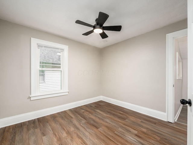 empty room featuring ceiling fan, dark wood finished floors, and baseboards