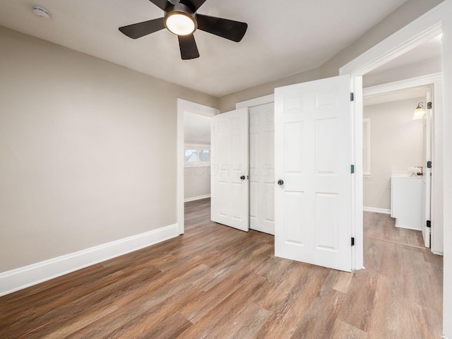 unfurnished bedroom featuring ceiling fan, a closet, baseboards, and wood finished floors