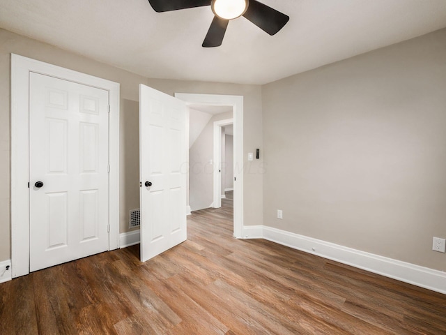 unfurnished bedroom with ceiling fan, wood finished floors, visible vents, and baseboards