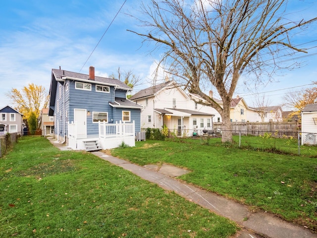 back of property with a fenced backyard, a chimney, central AC unit, and a lawn