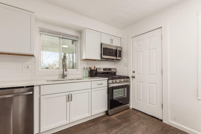 kitchen featuring white cabinets, decorative backsplash, stainless steel appliances, light countertops, and a sink