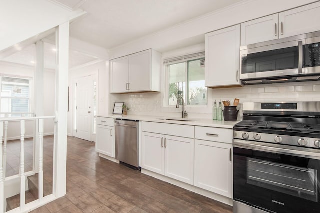 kitchen with light countertops, decorative backsplash, appliances with stainless steel finishes, ornamental molding, and a sink