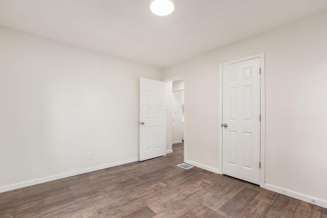 unfurnished bedroom featuring wood finished floors, visible vents, and baseboards