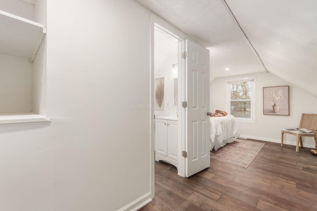 bedroom with vaulted ceiling, dark wood finished floors, and baseboards