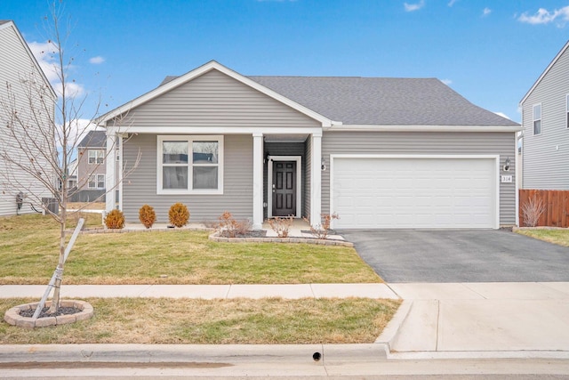 ranch-style home featuring a garage, driveway, roof with shingles, fence, and a front yard