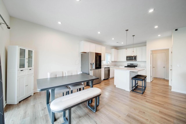 kitchen with appliances with stainless steel finishes, a kitchen island, a sink, and white cabinetry