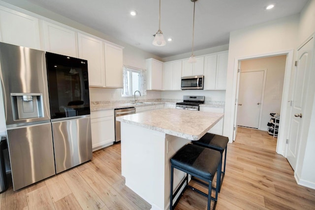 kitchen with appliances with stainless steel finishes, a center island, light countertops, and white cabinetry