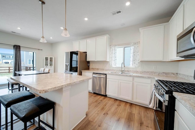 kitchen with visible vents, a breakfast bar area, stainless steel appliances, light wood-type flooring, and a sink